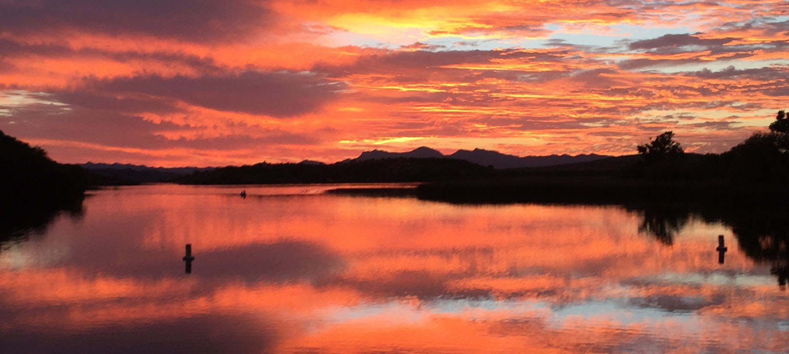 The sun sets over the lake with bright oranges and pinks